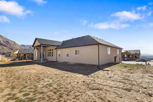 Rear view of house with a mountain view, a patio, and roof with shingles