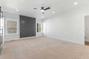 Unfurnished room featuring a barn door, light colored carpet, recessed lighting, and a ceiling fan