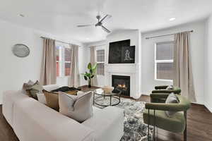 Living area featuring dark wood-style floors, a glass covered fireplace, a ceiling fan, a textured ceiling, and recessed lighting
