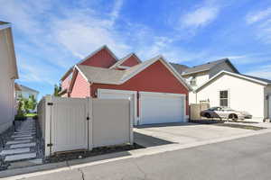 View of home's exterior with a gate, concrete driveway, a garage, and roof with shingles