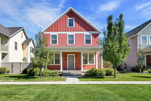 View of front of home featuring board and batten siding, a front lawn, covered porch, and a gate