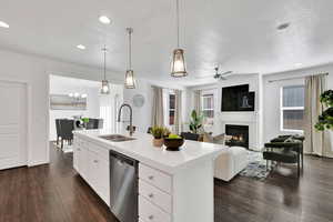 Kitchen with decorative light fixtures, white cabinetry, stainless steel dishwasher, open floor plan, and dark wood finished floors