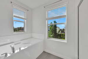 Bathroom with light tile patterned floors and a garden tub