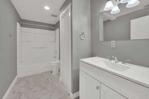 Bathroom with vanity, bathing tub / shower combination, light marble finish floors, and recessed lighting