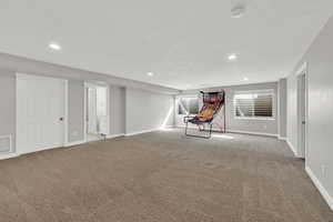 Below grade area with light colored carpet and recessed lighting