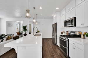 Kitchen featuring a kitchen breakfast bar, appliances with stainless steel finishes, light stone countertops, open floor plan, and hanging light fixtures