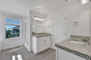 Full bath with two vanities, a shower stall, and light tile patterned floors