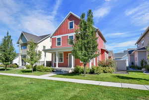 View of front of house featuring board and batten siding, a front yard, and covered porch