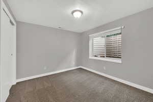Carpeted empty room with baseboards and a textured ceiling