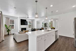 Kitchen with hanging light fixtures, white cabinetry, ceiling fan, open floor plan, and dark wood-style floors