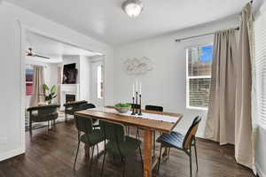 Dining room with a warm lit fireplace and dark wood finished floors