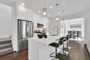 Kitchen with appliances with stainless steel finishes, a kitchen bar, an island with sink, tasteful backsplash, and white cabinets
