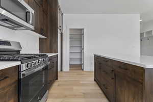 Kitchen featuring stainless steel appliances, light wood-style floors, and dark brown cabinets