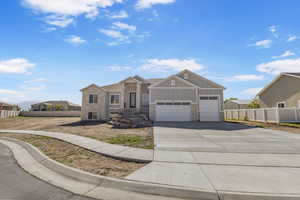 View of front of property with board and batten siding, driveway, a garage, and stone siding