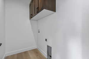 Laundry room with light wood finished floors, cabinet space, washer hookup, and hookup for an electric dryer