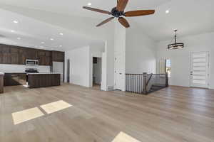 Unfurnished living room featuring recessed lighting, light wood-style floors, high vaulted ceiling, ceiling fan, and a chandelier