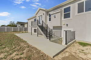 Rear view of house with a patio area, stucco siding, and stairway