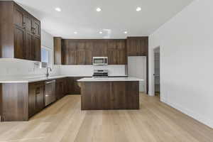 Kitchen with a kitchen island, dark brown cabinets, recessed lighting, appliances with stainless steel finishes, and light wood finished floors