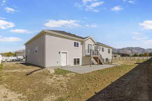 Rear view of house featuring a patio area, stucco siding, a mountain view, and stairs