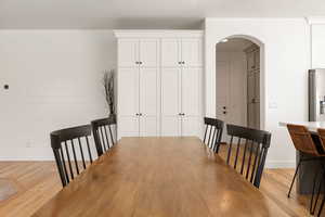 Dining area featuring light wood finished floors, arched walkways, and recessed lighting