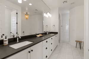 Bathroom with double vanity, a stall shower, light marble finish flooring, and recessed lighting