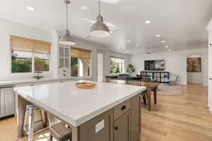 Kitchen featuring recessed lighting, hanging light fixtures, open floor plan, a kitchen bar, and light wood finished floors