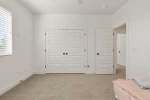 Bedroom featuring light carpet, a closet, and ceiling fan