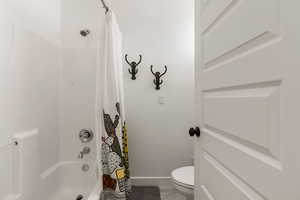 Full bath featuring shower / bath combo with shower curtain and toilet