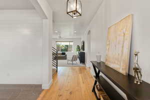 Corridor with arched walkways, light wood-type flooring, recessed lighting, stairway, and a chandelier