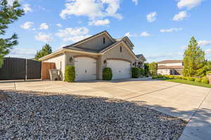 View of front facade featuring a gate, concrete driveway, stucco siding, and a garage