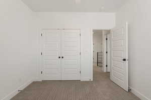 Unfurnished bedroom with carpet, a closet, and ceiling fan
