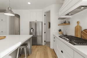 Kitchen featuring stainless steel appliances, white cabinets, recessed lighting, light wood finished floors, and custom range hood