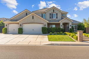 Traditional-style house with driveway, a garage, stucco siding, and brick siding
