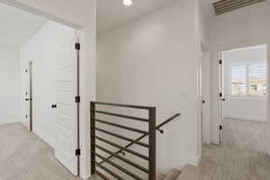 Corridor featuring light colored carpet and an upstairs landing