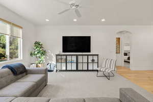 Living area with arched walkways, recessed lighting, light wood-type flooring, and ceiling fan