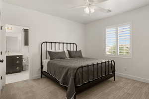 Bedroom with light colored carpet, a ceiling fan, and ensuite bath