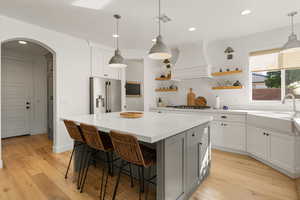 Kitchen with backsplash, recessed lighting, light wood-type flooring, a kitchen breakfast bar, and arched walkways
