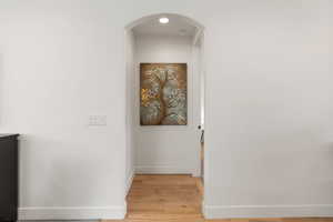 Corridor with light wood-style flooring and arched walkways