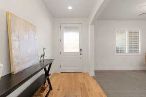 Foyer featuring light wood-style flooring, arched walkways, and recessed lighting