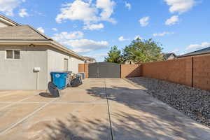 View of side of property featuring a gate, a fenced backyard, and stucco siding