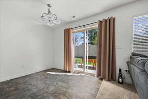 Unfurnished dining area featuring a chandelier and dark stone finish floors