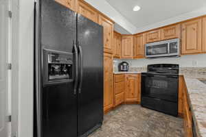Kitchen with black appliances, recessed lighting, and light stone counters