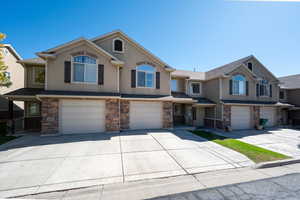 View of front of property featuring an attached garage, driveway, and stucco siding