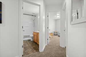 Hall with dark colored carpet and baseboards