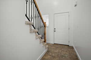 Foyer featuring stairway and dark stone finish floors