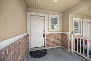 View of exterior entry with brick siding and stucco siding