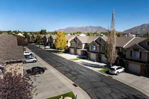 View of asphalt road featuring a residential view, a mountain view, sidewalks, and curbs