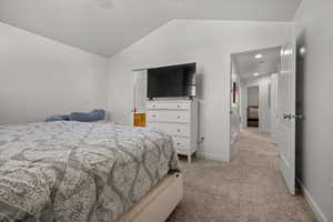 Bedroom with vaulted ceiling and light carpet