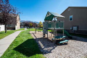 Community play area with a mountain view and a yard