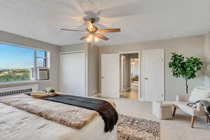 Carpeted bedroom featuring radiator, a closet, ceiling fan, and cooling unit